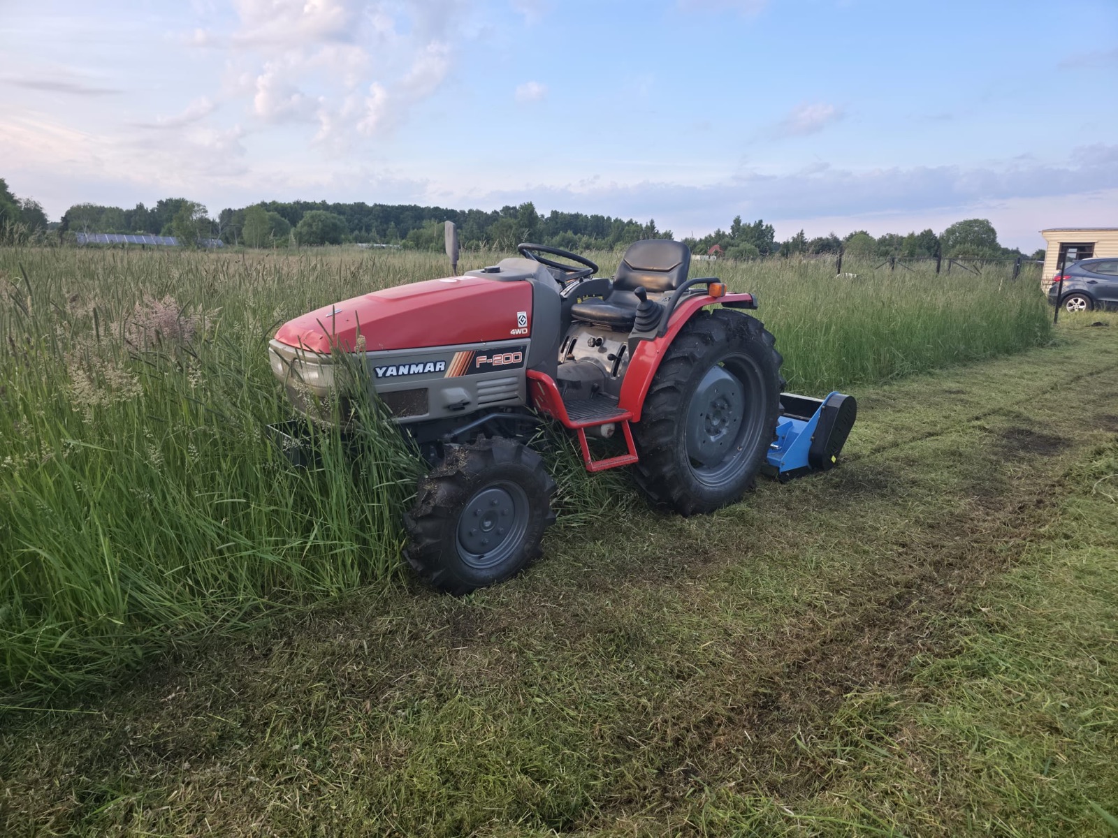 Ciągnik z kosiarką bijakową w wysokiej trawie
